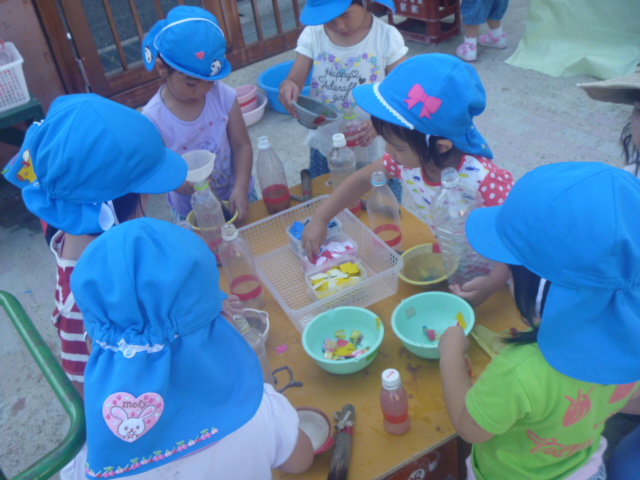 3歳児が園庭で友だちと色水遊びをしている