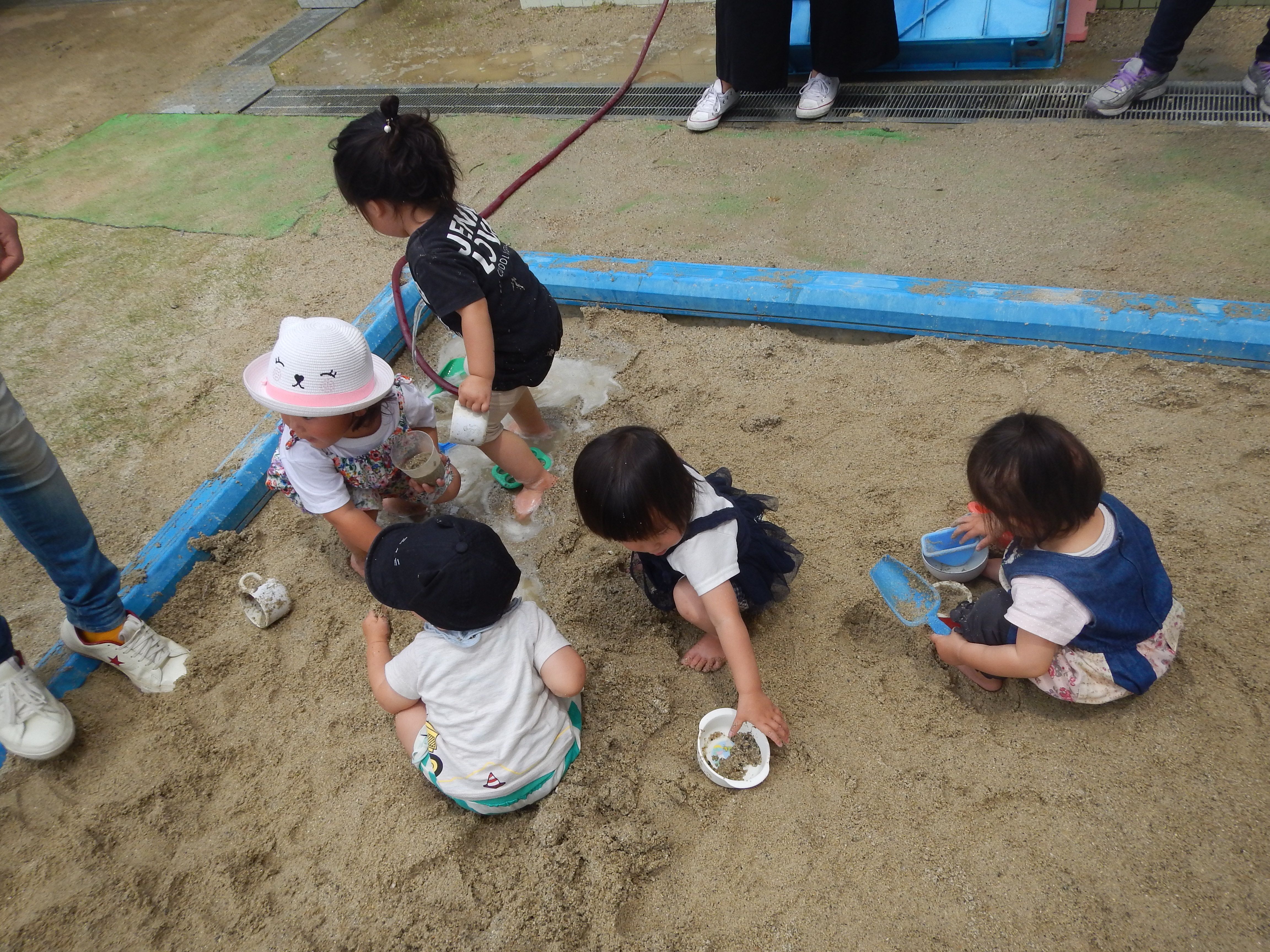 砂場で砂の感触を楽しんで遊んでいる