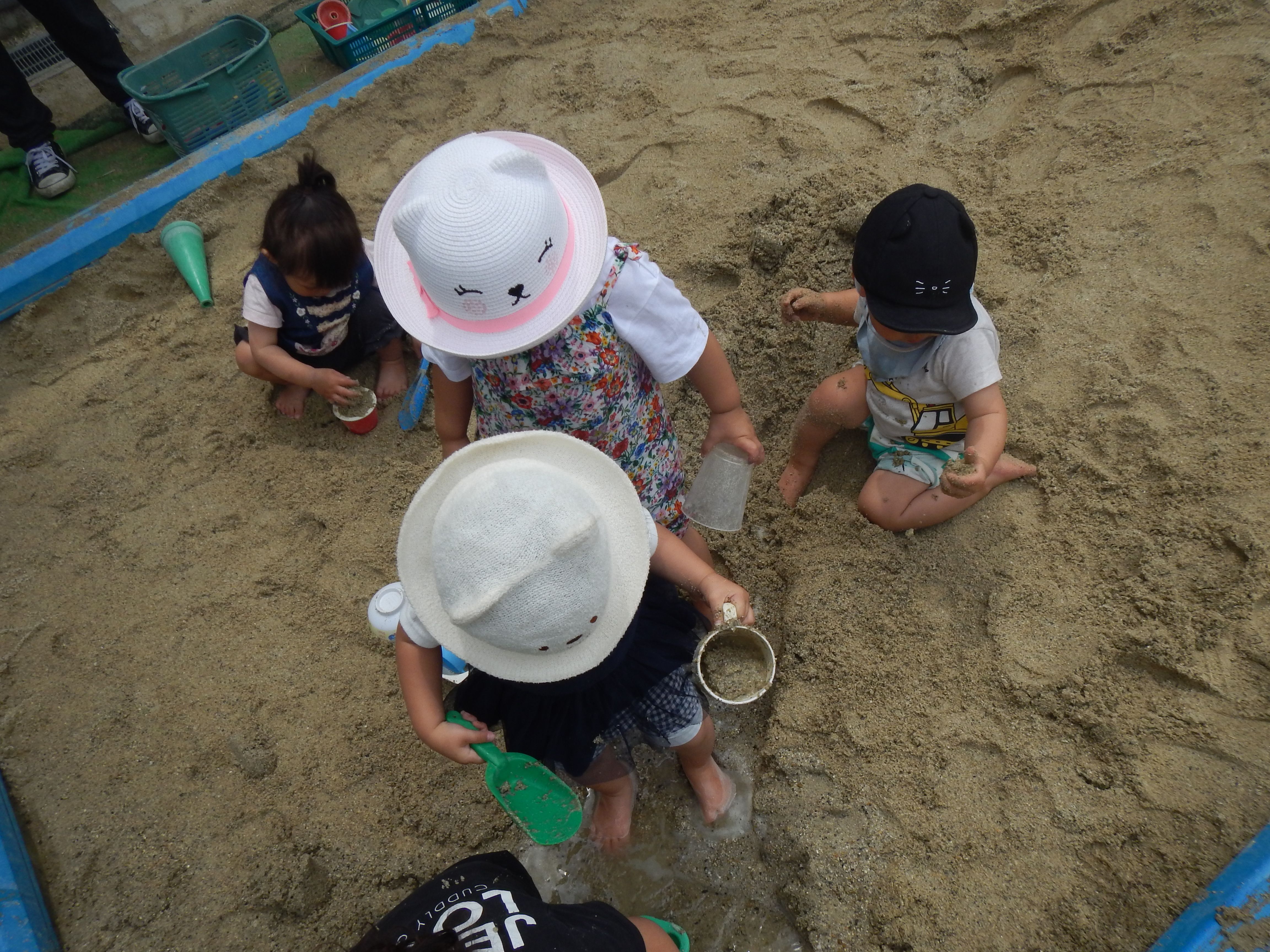 砂をスコップですくってカップに入れて遊んでいる