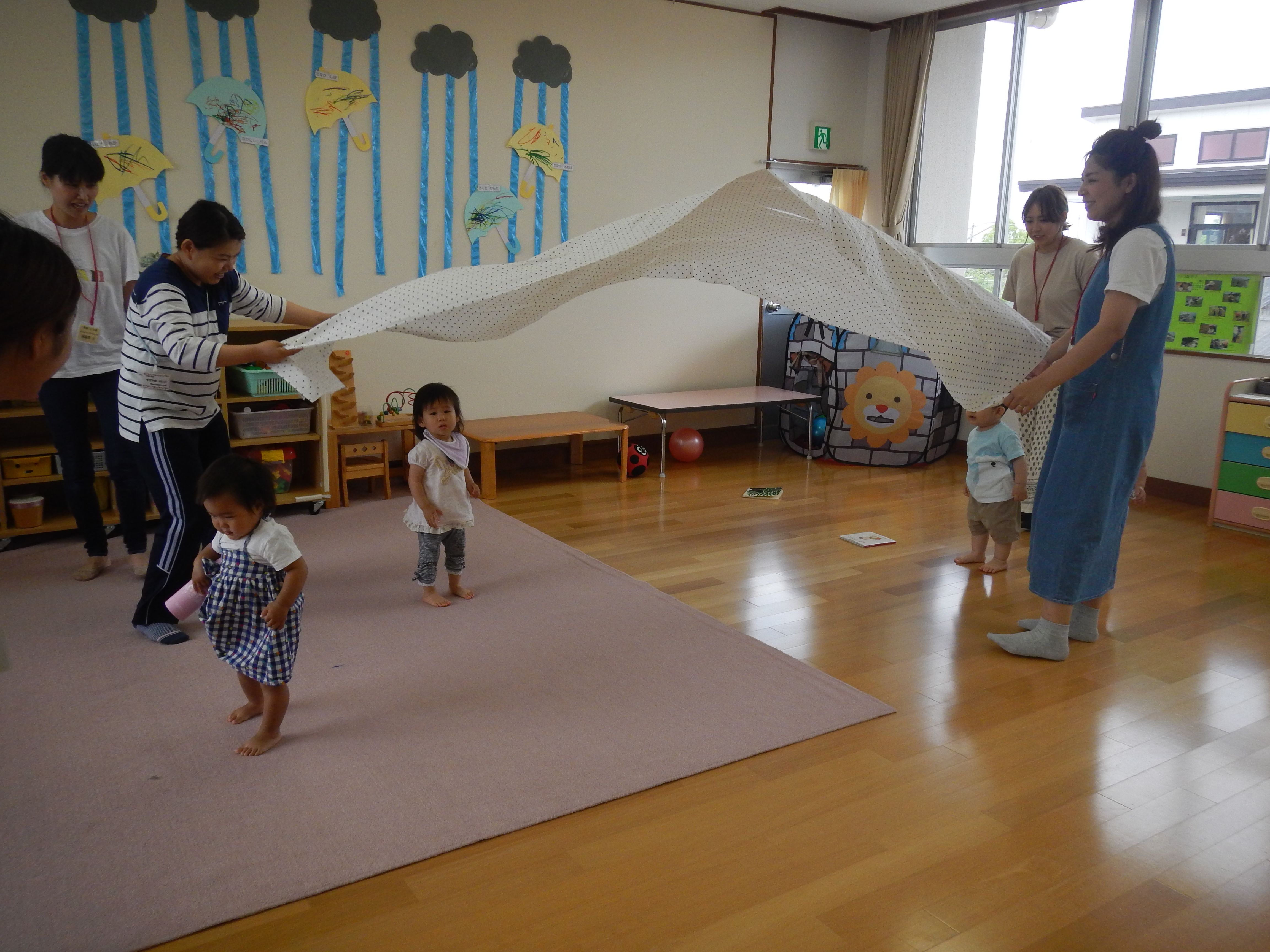 大きな布を上下に揺らして風を感じて通り抜けて遊んでいる