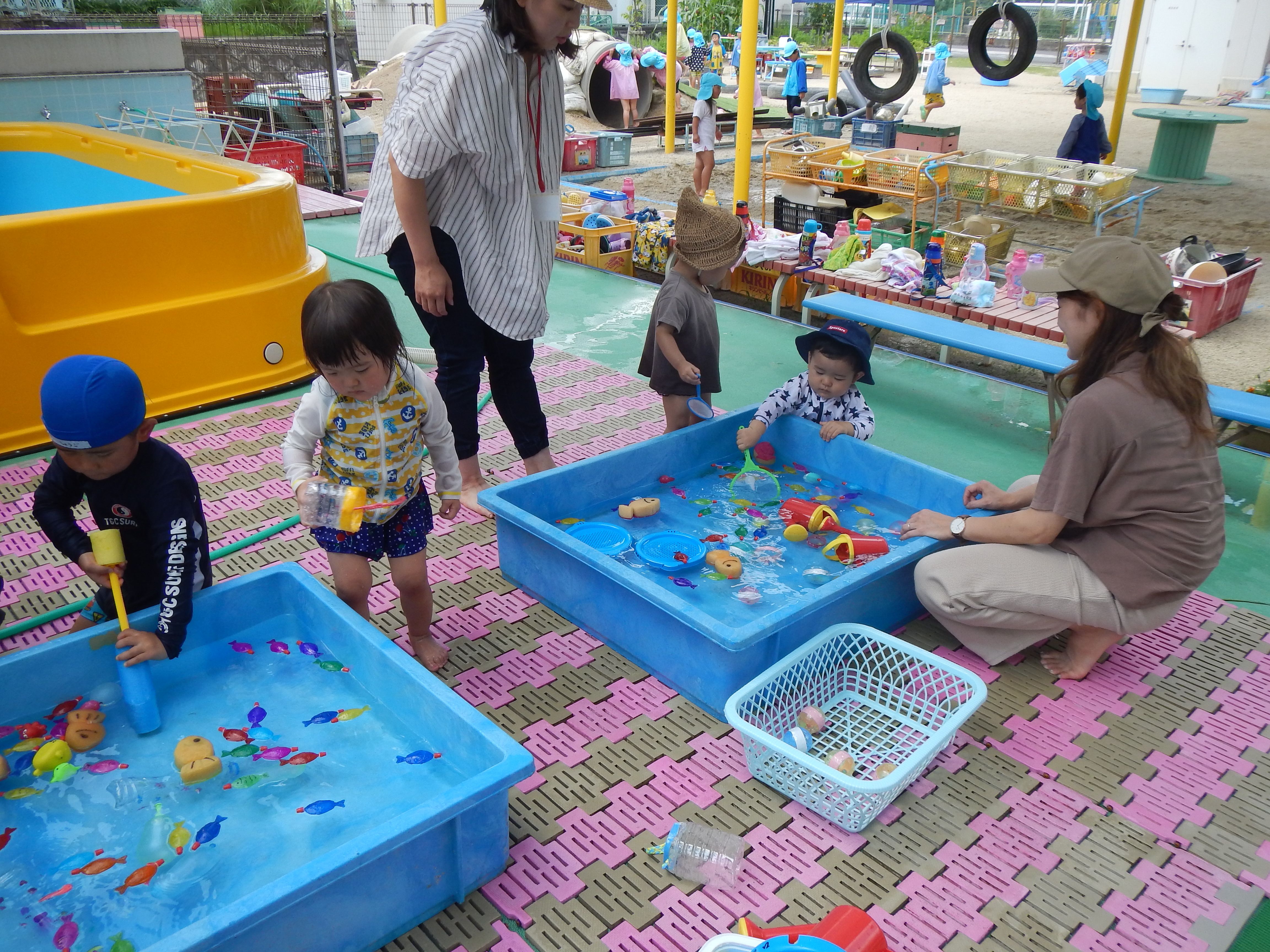 タライの中の水に浮いている魚のおもちゃをアミですくっている