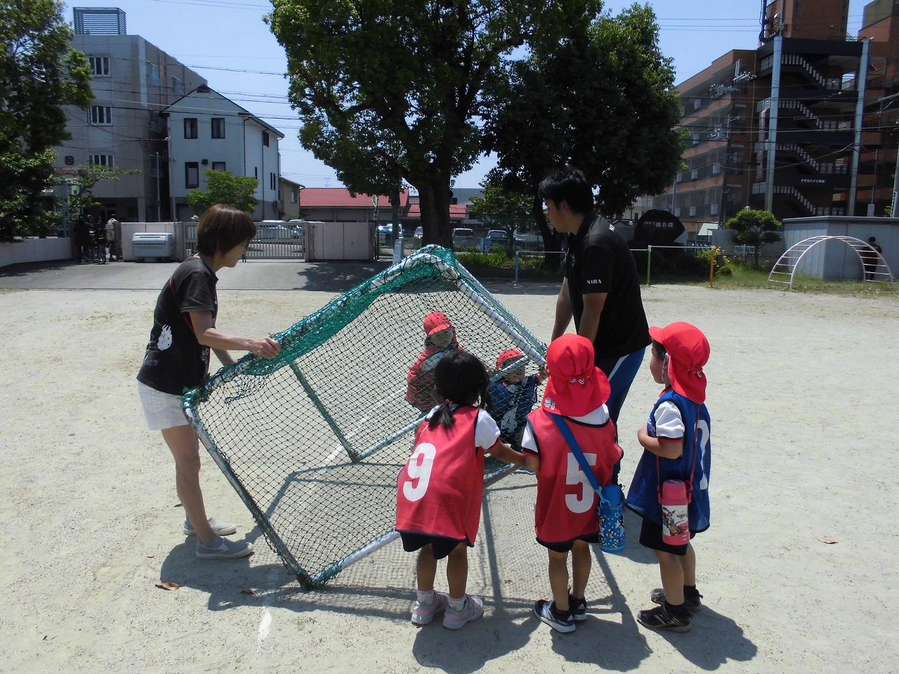 サッカーゴールの片付けを手伝う4歳児