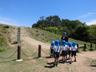 担任の先生から古墳の話を聞く5歳児