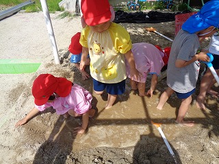 砂場で泥んこ遊びをする子どもたち