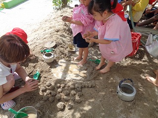 砂場で泥だんご作りに挑戦する4歳児