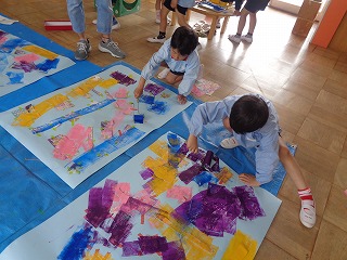 ローラーでこいのぼりの色を塗る5歳児